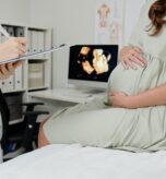 Close-up of doctor making notes in medical card after ultrasound exam of pregnant woman at hospital